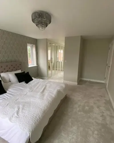 Freshly painted pale grey bedroom with a feature wallpaper behind the bed
