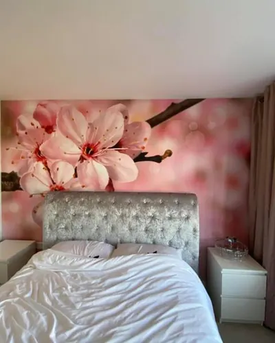 Bedroom with a pink cherry blossom wall mural behind the bed
