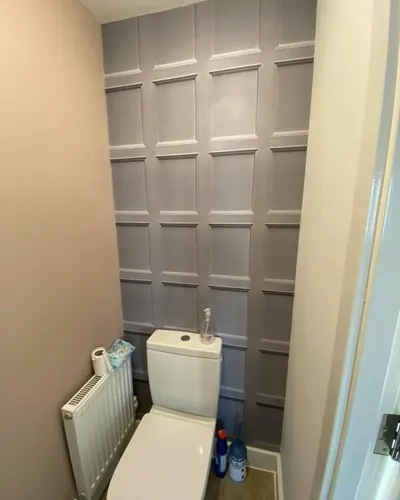 Grey wall panelling in a small cloakroom with a white toilet