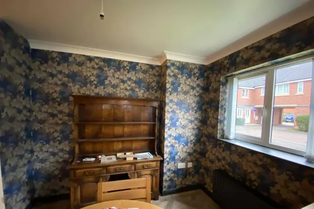 Living room hung with a blue and gold floral wallpaper